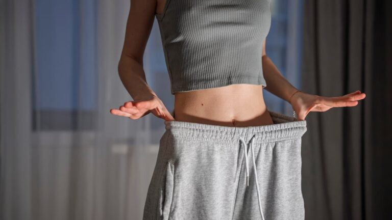 Woman showing weight loss transformation results wearing oversized pants