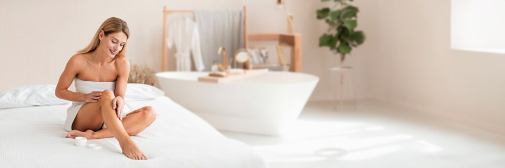 Woman moisturizing her smooth legs as part of laser hair removal aftercare